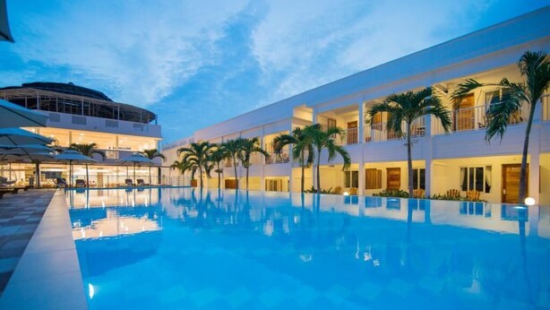 Ein Hotel mit Schwimmbad, mehreren Balkonen und Palmen.