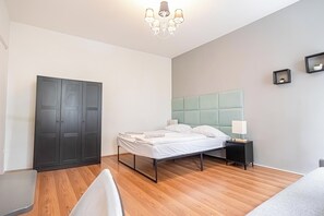 A bedroom with a bed, bedside table, lamp, wardrobe, and a chandelier. - Stylish 1BR Apt Danube Near Prater Park (Vienna)