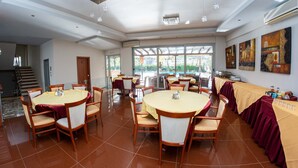 A conference room with round tables, chairs, and a long table with a tablecloth. - Hotel Ena - Cozy Mountain View Suite With Pool (Lamia)