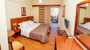 A hotel room with two beds, a desk, a chair, a TV, and a balcony with patterned curtains. - Hotel Ena - Cozy Mountain View Suite With Pool (Lamia)