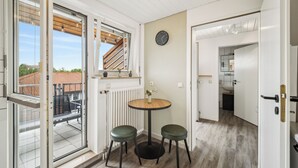 Huoneessa on liukuovella varustettu lasiterassi, jolta on pääsy parvekkeelle. Lisäksi huoneessa on pyöreä puupöytä, jossa on kaksi vihreää jakkaraa, seinäkello ja patteri.