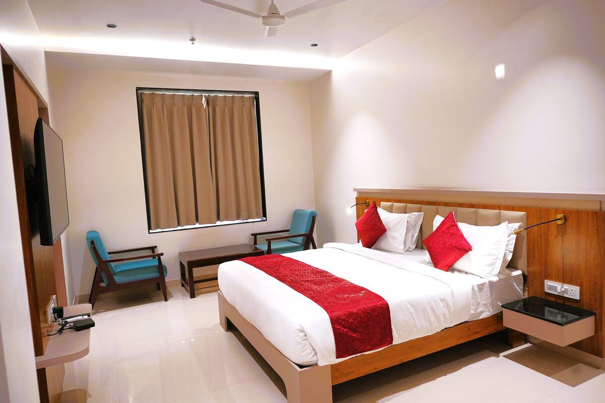 Una habitación de hotel con una cama grande, televisión, escritorio y una silla.