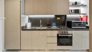 Una cocina moderna con un lavamanos de acero inoxidable, una estufa y un microondas. Hay una manta ignífuga en la pared y un cartel que indica un aviso de incendio.