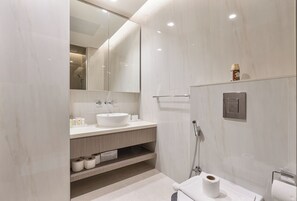 Un baño moderno con un espejo grande, un lavabo blanco, ducha y retrete.
