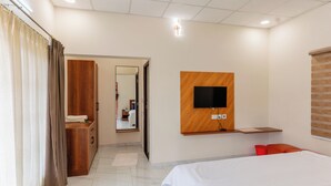 Une chambre d’hôtel avec un lit, un téléviseur fixé au mur, une armoire en bois et un miroir.