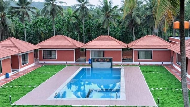 Un complexe hôtelier comprenant plusieurs villas aux toits rouges, une piscine centrale et une végétation luxuriante.