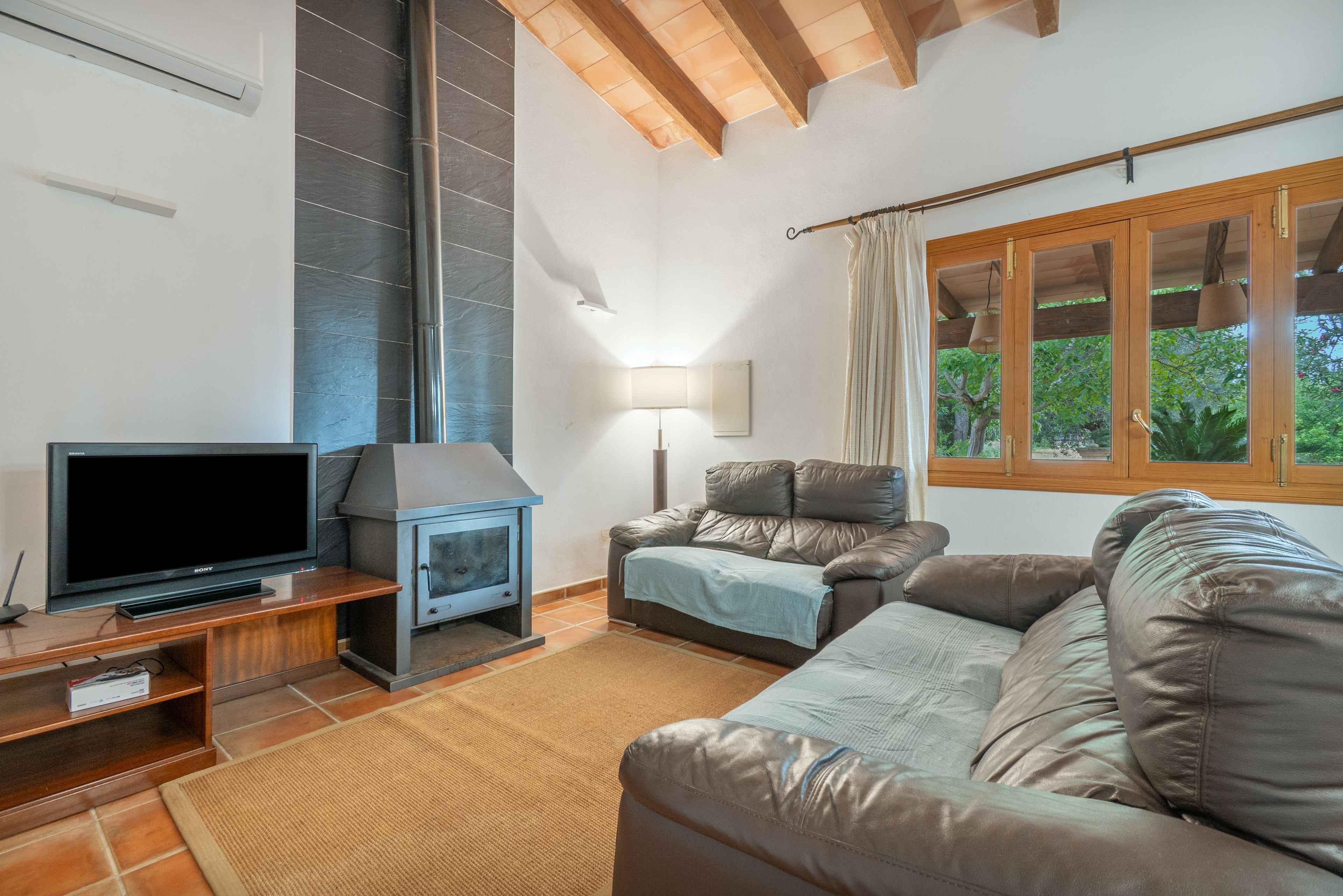 Ein Wohnzimmer mit Fernseher, Kamin, einer Couch und einem Fenster mit Vorhängen.