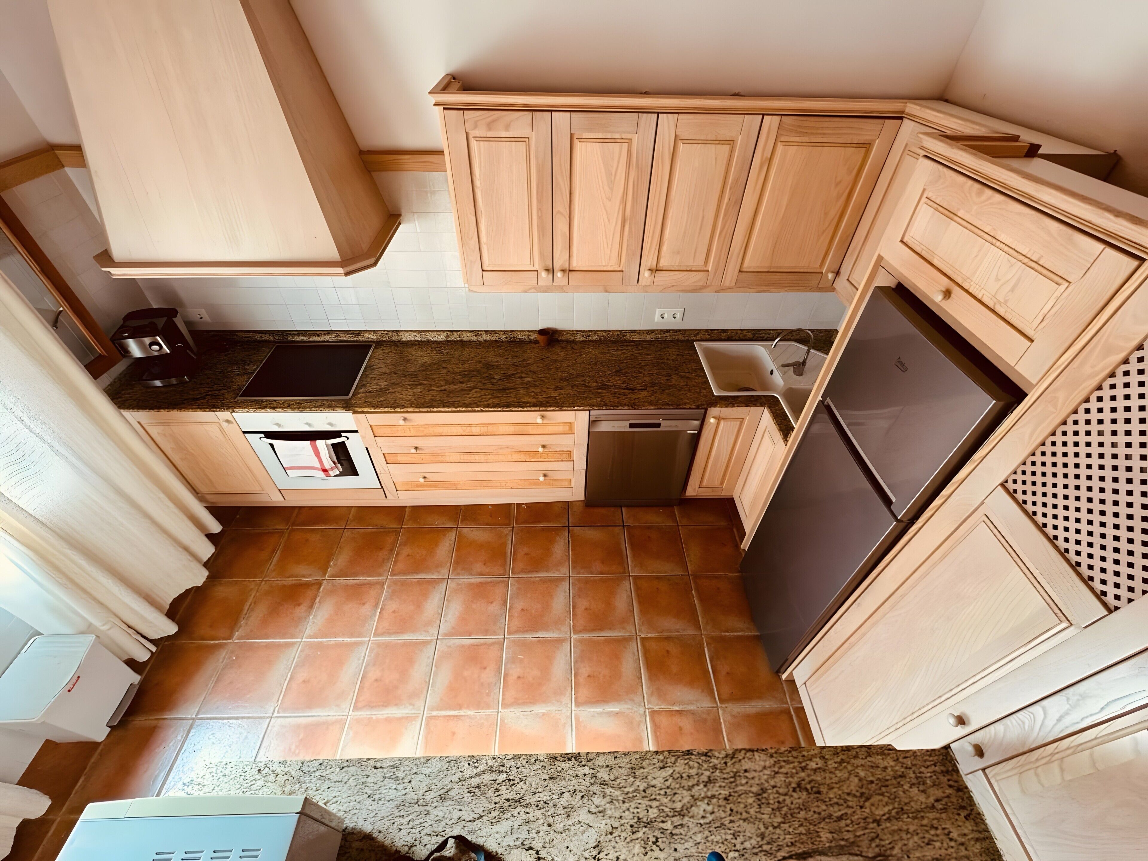 Eine kompakte Küche mit Holzausstattung, einem integrierten Geschirrspüler und einem Edelstahlkühlschrank.