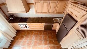 Eine kompakte Küche mit Holzausstattung, einem integrierten Geschirrspüler und einem Edelstahlkühlschrank.