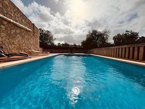 Una piscina con muros de piedra y un cielo azul despejado.