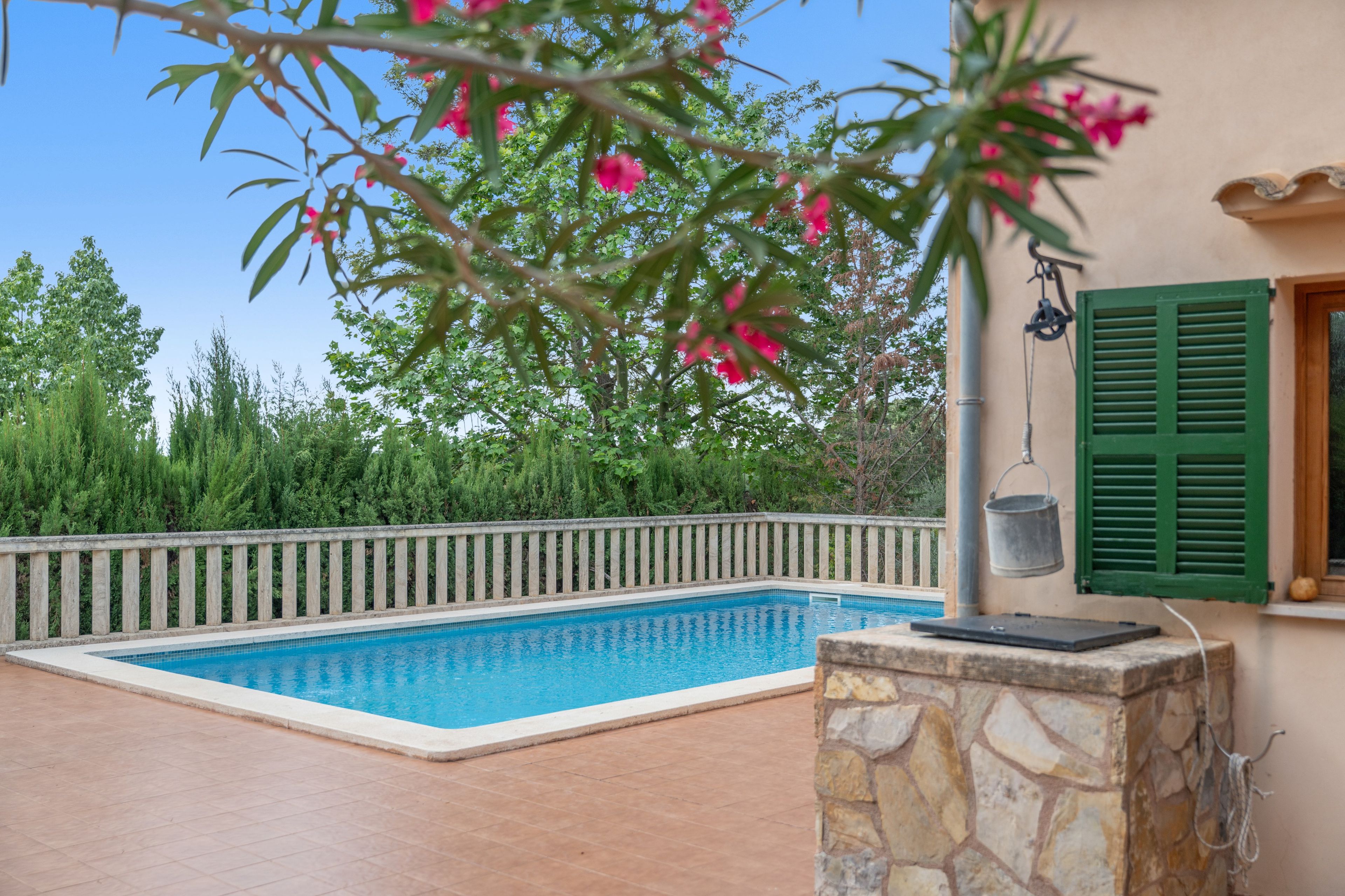 Une piscine avec un mur en pierre et un seau en métal sur un balcon.