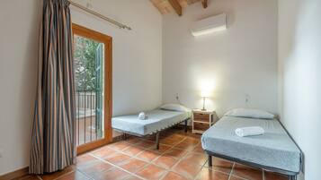A room with two beds, a window with a curtain, a nightstand with a lamp, and a tiled floor.