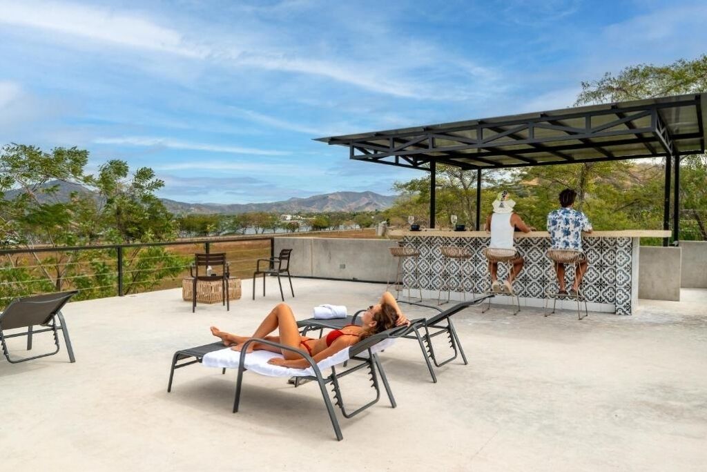 Un salon sur le toit doté d’une piscine, de chaises longues et d’un bar offrant une vue sur les montagnes.