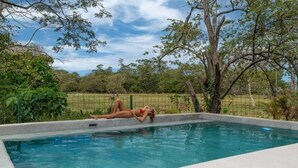 A rectangular swimming pool with a person lying on the edge. - HOTEL NELBLU #9 - QUEEN DOUBLE BED (Playa Flamingo)