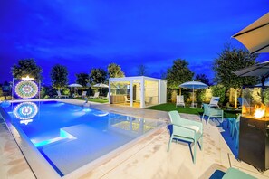 Une piscine dotée de chaises longues et d’un foyer extérieur.