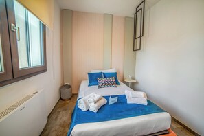 A hotel room with a bed, a window, a bedside table, and a trash bin. - Alternative Resort & SPA Apartments (Scorrano)