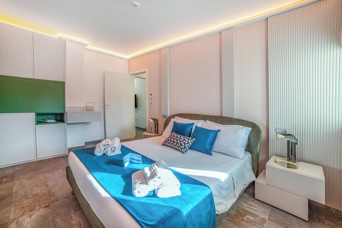 A modern hotel room with a bed, bedside table, and built-in wardrobe.