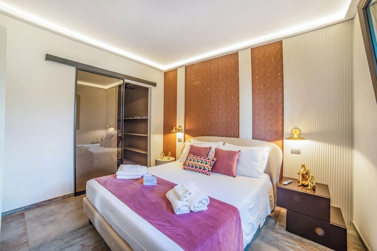 A hotel room with a bed, a nightstand, a wall-mounted lamp, and a sliding door closet.