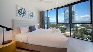 Ein modernes Schlafzimmer mit einem großen Bett, einem Deckenventilator und Blick auf die Stadt durch raumhohe Fenster.