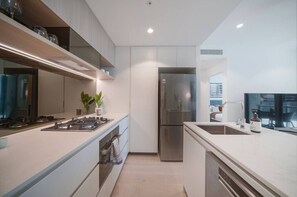 Eine moderne Küche mit Einbauherd, Backofen und einem Edelstahl-Kühlschrank.