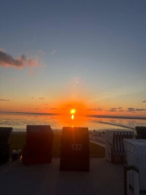 A sunset view from a beachside lounge with lounge chairs and a sign with the number 132.