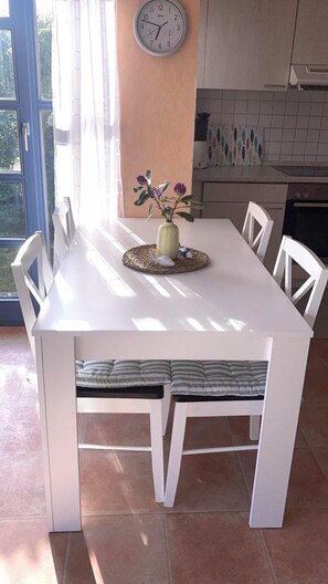 Una mesa de comedor con sillas, un reloj en la pared y un florero con flores.