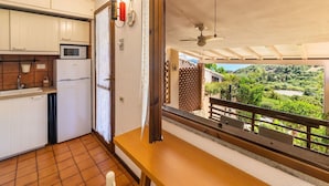 Eine Küche mit Mikrowelle, Kühlschrank und Fenster mit Blick auf eine grüne Landschaft.