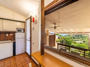 Eine Küche mit Mikrowelle, Kühlschrank und Fenster mit Blick auf eine grüne Landschaft.