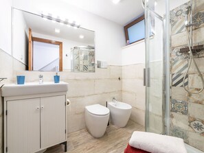 A bathroom with a white vanity, two toilets, a shower with a glass door, and a mirror with lights. - Wonderful private villa for 4 guests with WIFI, A/C, TV, patio and pets allowed (Quartu Sant'elena)