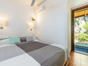 A bedroom with a bed, two wall-mounted lights, an air conditioning unit, and a view of a balcony with plants. - Wonderful private villa for 4 guests with WIFI, A/C, TV, patio and pets allowed (Quartu Sant'elena)