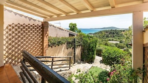 Ein Balkon mit Blick auf eine Küstenlandschaft, einer Pergola und einem Holgitter.