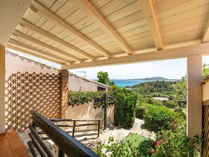 Ein Balkon mit Blick auf eine Küstenlandschaft, einer Pergola und einem Holgitter.