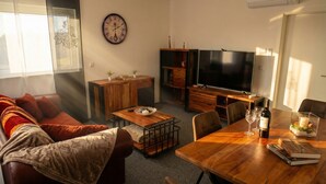 Uma sala de estar com sofá, mesa de centro, televisão e mesa de jantar com cadeiras.