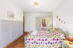Une chambre à coucher avec un lit, une armoire, une table de chevet et une lampe.