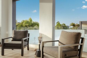 Ein Balkon mit zwei Stühlen, einem Glastisch und einer Champagnerflasche.