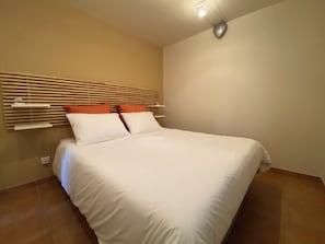 A bedroom with a bed, a headboard, and a wall-mounted light fixture.