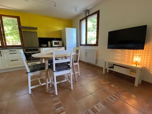 Une cuisine avec des meubles blancs, un four à micro-ondes, une cuisinière et un coin repas comprenant une table et des chaises.