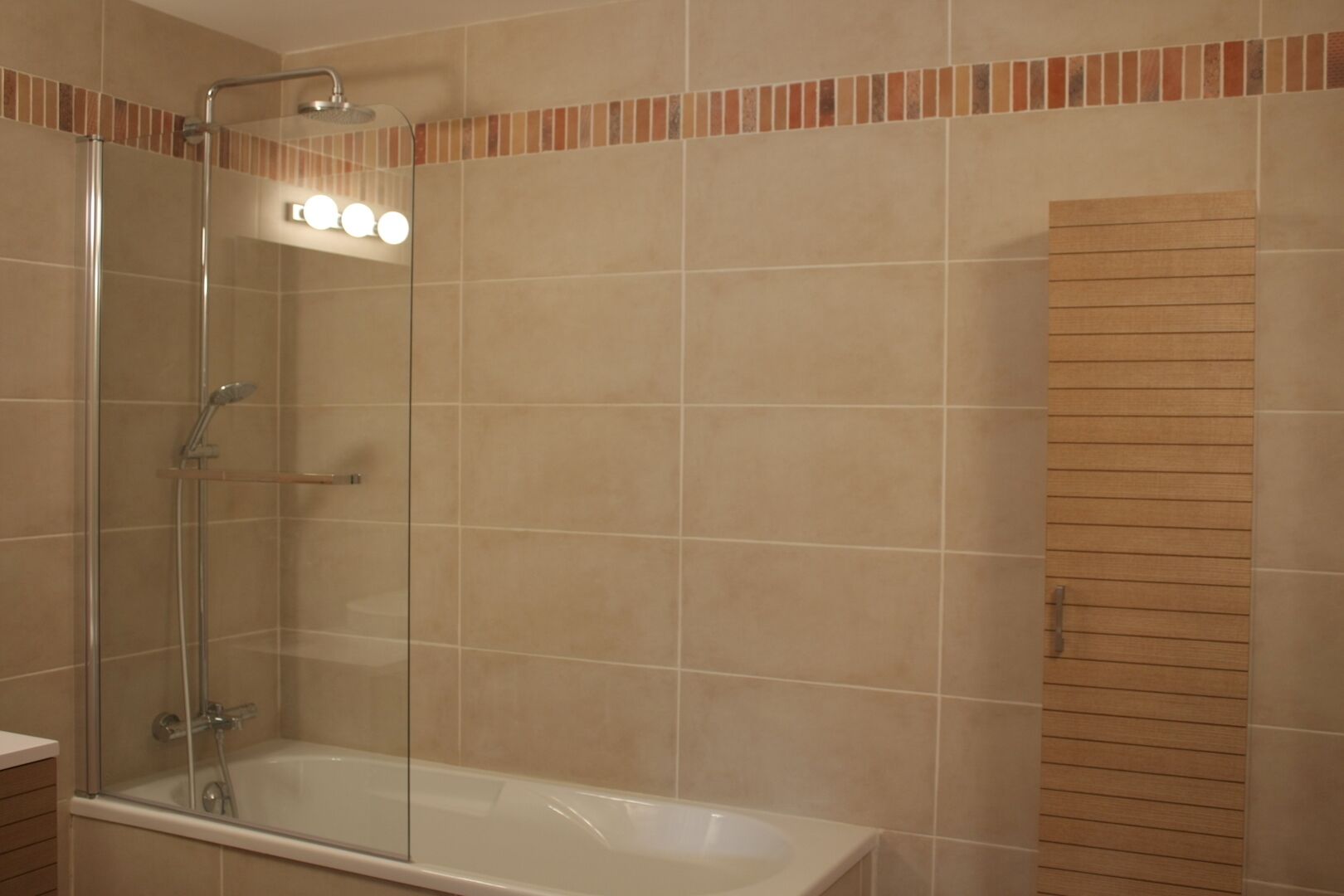 Ein Badezimmer mit einer gläsernen Duschkabine, einer Badewanne und einer Wand aus Holzpaneelen.