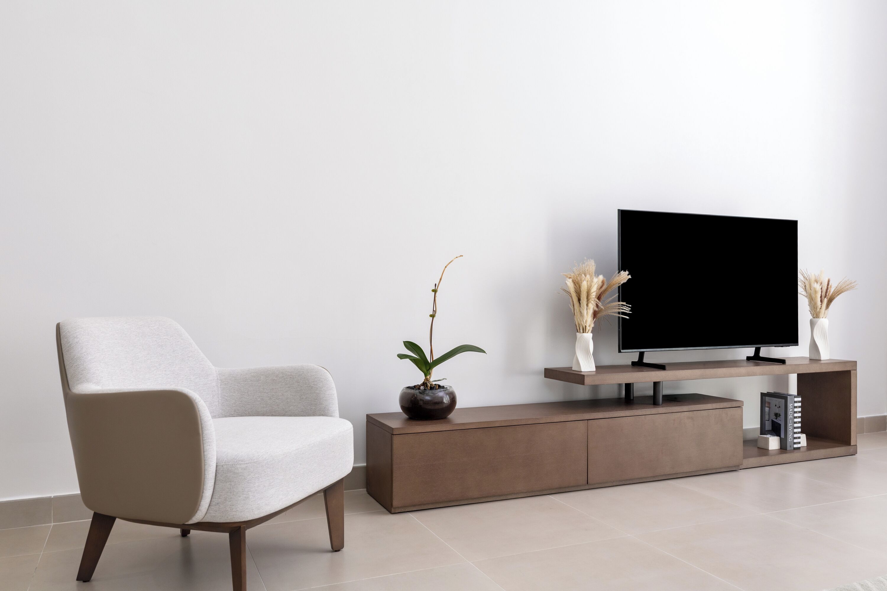 A modern living room with a sofa, a flat-screen TV, a console table, and decorative plants.