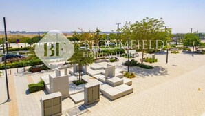 A spacious outdoor area with modern seating arrangements and greenery, likely part of a holiday home or resort. - Bloomfields Deluxe 1Br Leonardo (Abu Dhabi)