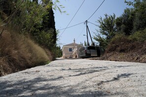 A narrow road leading to a house with a car parked on the side.
