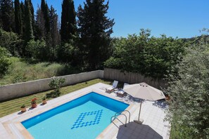 Ein rechteckiger Swimmingpool mit einem geometrischen Muster am Rand, umgeben von einer gefliesten Terrasse.