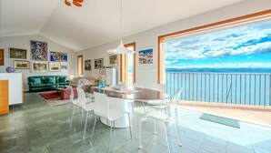 A modern living room with a dining area, large windows with a view of the sea, and artwork on the walls. - Villa Perfect house beachfront by Villas Guide (Lovran)