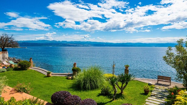 A scenic garden with a bench overlooking a lake, surrounded by mountains. - Villa Perfect house beachfront by Villas Guide (Lovran)