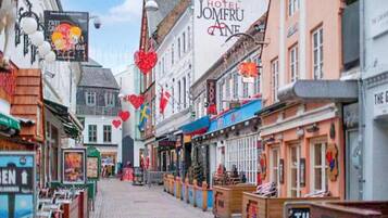 A street with a hotel named 'Hotel Jomfru Ane' and various shops.