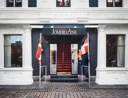 La entrada del Hotel Jomeroane con una puerta roja, dos banderas y un letrero.