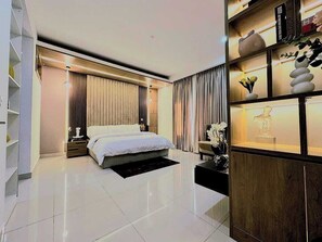 A modern bedroom with a large bed, a bedside table, a nightstand, a wooden cabinet with decorative items, and a bookshelf. - Masters Lodge (Abuja)