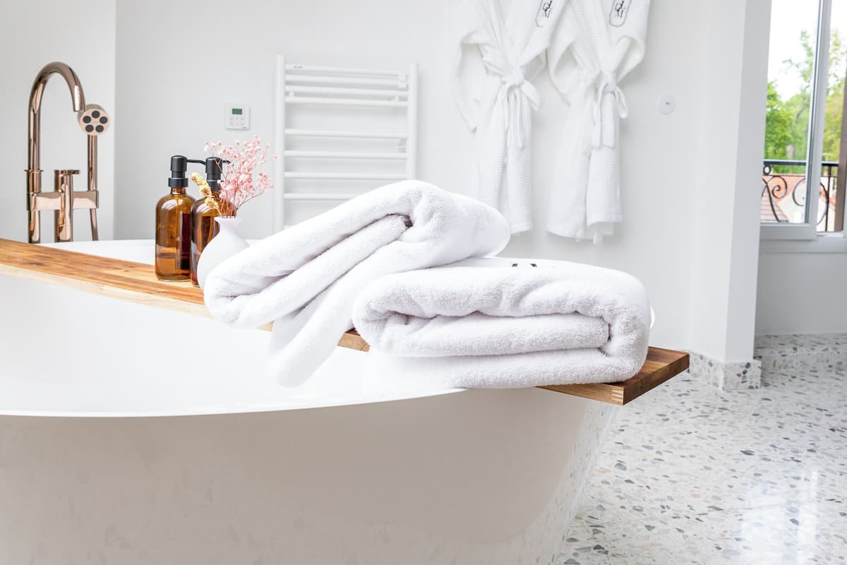 A modern bathroom with a freestanding bathtub, white towels, and a wooden vanity.