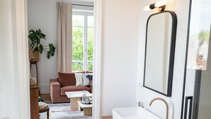Un baño moderno con un lavamanos blanco, un espejo y una ducha.