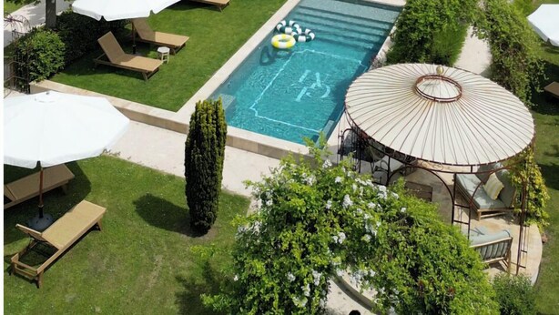 Una casa grande con piscina, mobiliario de exterior y jardín.